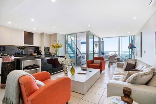 a large living room with orange chairs and a couch at Lookout 334 - Endless Ocean Views - Rooftop Spa in Kingscliff