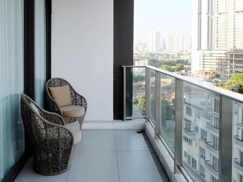 a balcony with a chair and a view of a city at Mangkuluhur Residences by Lorin in Jakarta