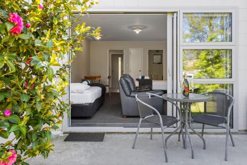 a patio with a table and chairs and a living room at ASURE Brookvale Motel in Wanaka