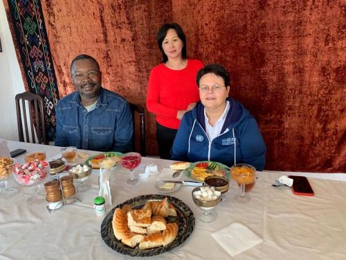 Un groupe de trois personnes assises à une table avec de la nourriture dans l'établissement Guest House KAGAN, à Toktogul