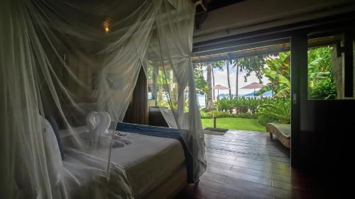 a bedroom with a bed and a view of the ocean at Last Frontier Beach Resort-Adults Only in El Nido