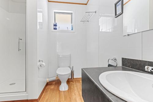 Baño blanco con lavabo y aseo en ASURE Brookvale Motel, en Wanaka