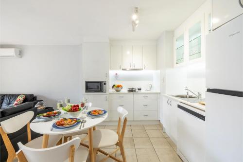 a white kitchen with a table with food on it at Nelson Bay Breeze Apartment, 29,1 Trafalgar Street - Air conditioned unit with Linen supplied, complex pool and spa in Nelson Bay