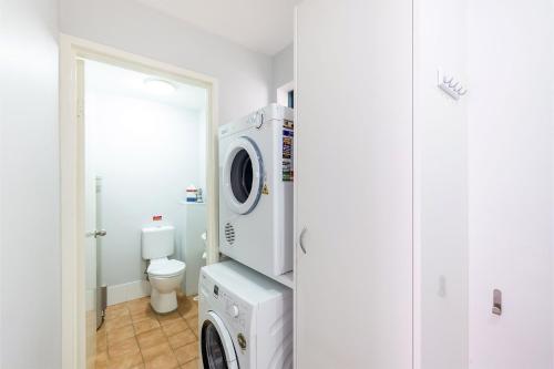 a bathroom with a washing machine and a toilet at Nelson Bay Breeze Apartment, 29,1 Trafalgar Street - Air conditioned unit with Linen supplied, complex pool and spa in Nelson Bay