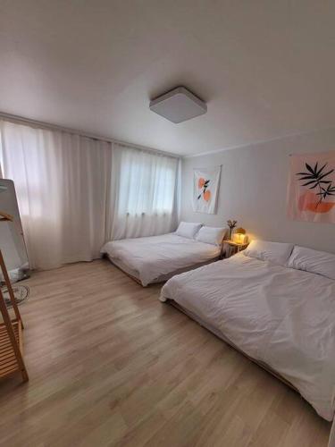 two beds in a room with white walls and wooden floors at Reve Guwol in Incheon