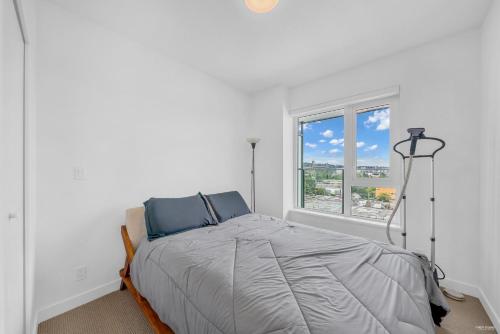 a white bedroom with a bed and a window at Kind One Bedroom Apartment in North Vancouver