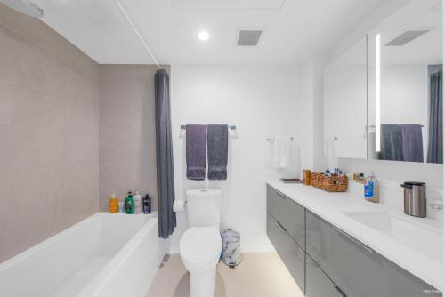 a white bathroom with a toilet and two sinks at Kind One Bedroom Apartment in North Vancouver