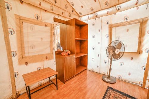 Shama Desert Camp & Resort في Sām: غرفة بها مروحة ومكتب