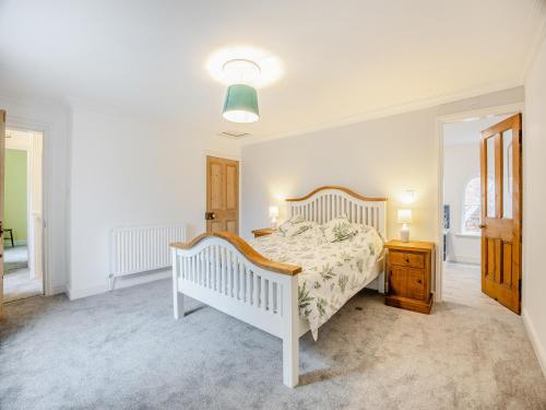 a white bedroom with a bed and a night stand at Misdale House in Louth