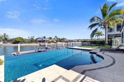 a swimming pool next to a body of water at YALLA24-Luxury Resort Style Home in Mooloolaba