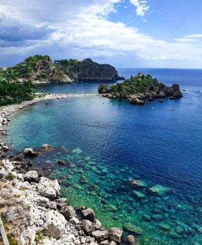 an island in the ocean with rocks and reefs at Alba Marina e Tramonti Etnei in Riposto