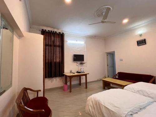 a room with two beds and a table and a tv at The Patel Stadium Hotel 1 Km from Bus Stand and 2 Km from Railway station in Ajmer