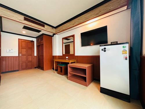 a room with a refrigerator and a desk and a tv at Sawasdee Apartment Patong in Patong Beach