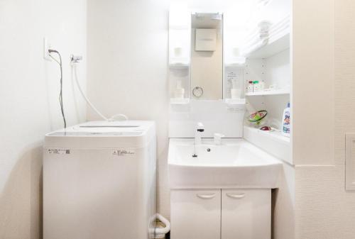een witte badkamer met een wastafel en een spiegel bij RLiS-house Shin-Osaka Kita - Vacation STAY 9525 in Osaka
