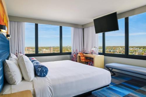 a bedroom with a large white bed and large windows at Aloft South Bend in South Bend