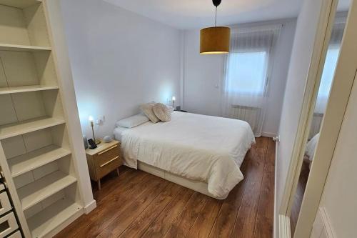 a small bedroom with a white bed and shelves at Occidente Costa Verde Asturiana 