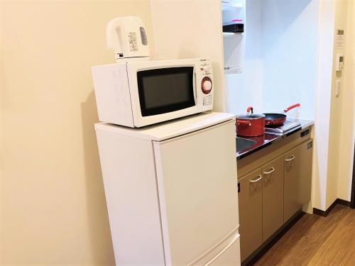 een magnetron bovenop een koelkast in een keuken bij RLiS-house Shin-Osaka Kita - Vacation STAY 9516 in Osaka