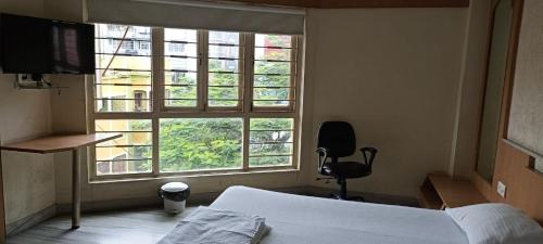 sypialnia z łóżkiem i dużym oknem w obiekcie Ballygunj Guest House w mieście Kolkata