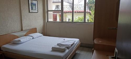 Ballygunj Guest House في كولْكاتا: سرير في غرفة مع نافذة