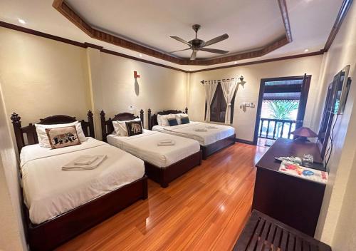 a bedroom with two beds and a ceiling fan at Y Not Lao Villa in Luang Prabang