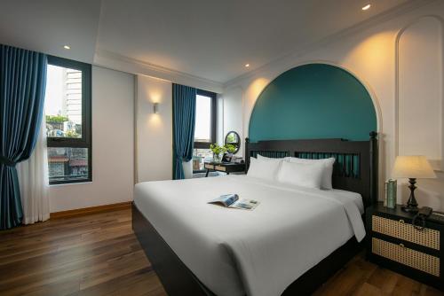 a bedroom with a large white bed with blue accents at Hotel De Rond in Hanoi