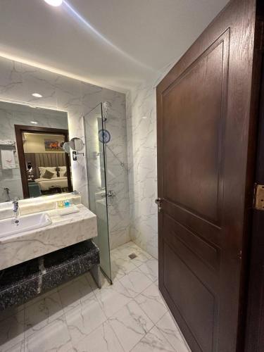 baño con lavabo, ducha y puerta en Lophorina Hotel en Al ‘Abābīd