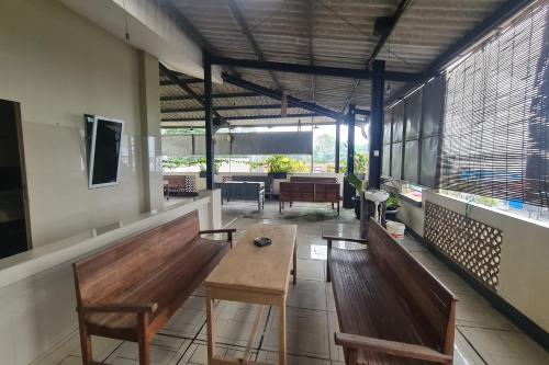 a room with benches and a table and windows at Capital O 93250 Hotel Tirta Kencana 2 Baturaden in Banyumas