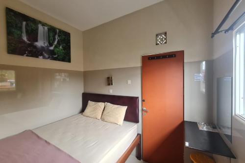 a small bedroom with a bed and a wooden door at Capital O 93250 Hotel Tirta Kencana 2 Baturaden in Banyumas