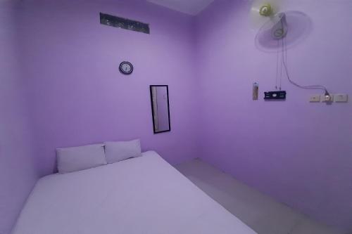 een witte kamer met een bed en een klok aan de muur bij SPOT ON 93283 Sengon Kostel Syariah in Jepara