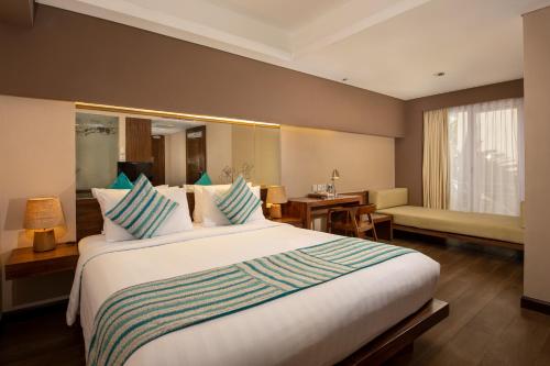 a hotel room with a large bed and a desk at Grand Ixora Kuta Resort in Kuta