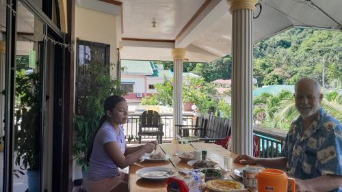 un homme et une femme assis à une table qui mangent de la nourriture dans l'établissement Riverside at Aninuan Accommodation and Food, à Puerto Galera