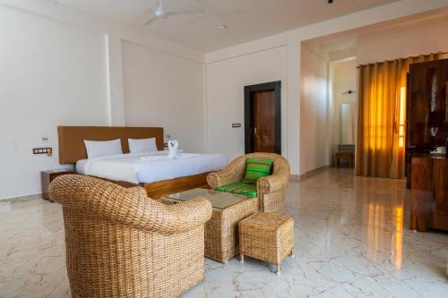 a hotel room with a bed and wicker chairs at The Kaziranga Address in Kāziranga