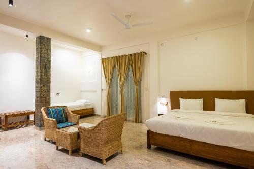 a bedroom with a bed and wicker chairs in it at The Kaziranga Address in Kāziranga