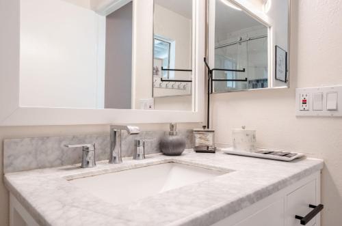 a bathroom with a white sink and a mirror at Elegant Retreat w/ Game room in Heart of OC in Midway City