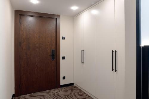 a hallway with a wooden door and white walls at Almaty Hotel in Almaty