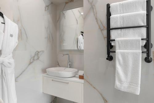 a white bathroom with a sink and a mirror at Almaty Hotel in Almaty