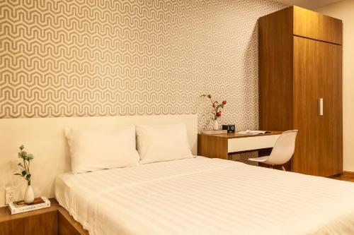 a bedroom with a white bed and a desk at The Jade Apartment in Ho Chi Minh City