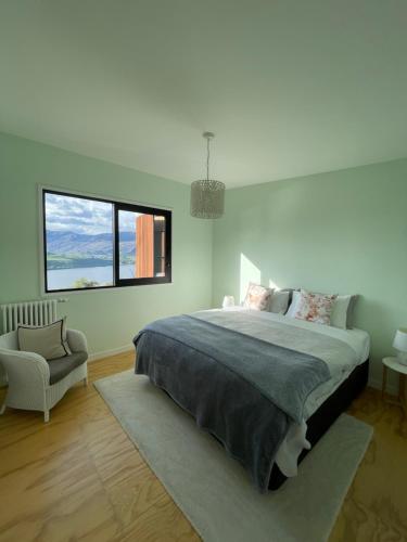a white bedroom with a large bed and a chair at Lake view apartment La Hay 66 in Queenstown