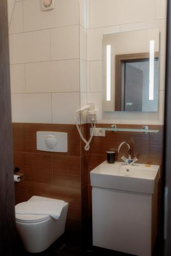 a bathroom with a toilet and a sink and a mirror at NED Hotel in Graz