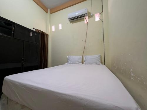 ケンダリにあるHotel O Mely Homestayの白いベッド1台、壁にエアコンが備わるベッドルーム1室が備わります。