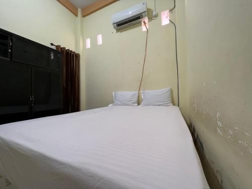 um quarto com uma cama com lençóis brancos e um aquecedor em OYO 93309 Mely Homestay em Kendari