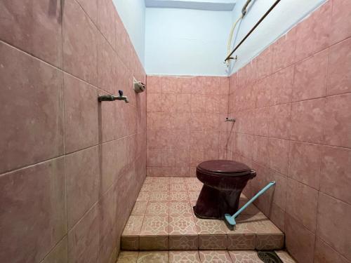 a bathroom with a toilet in a pink tiled shower at OYO 93309 Mely Homestay in Kendari