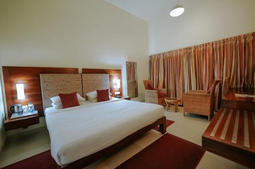 a hotel room with a large bed and a chair at Devaragam in Guruvāyūr