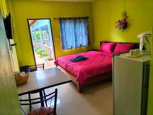 a bedroom with a bed with pink pillows and a table at Lanta Blue House in Ko Lanta
