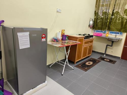 a kitchen with a refrigerator and a table in it at Wafiy Homestay in Macang