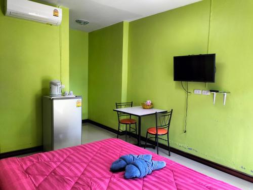 a room with a bed and a table and a tv at Lanta Blue House in Ko Lanta