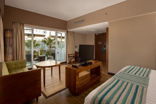 a hotel room with a bed and a television at Grand Ixora Kuta Resort in Kuta