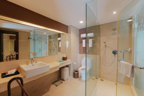 a bathroom with a sink and a shower at Grand Ixora Kuta Resort in Kuta