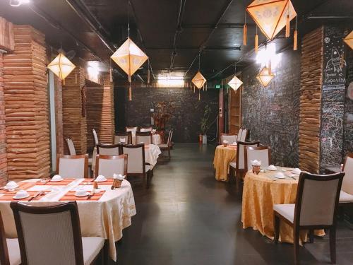 una sala da pranzo con tavoli, sedie e luci di Little Gold Hue boutique hotel a Hue