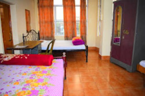 Zimmer mit einem Bett, einem Tisch und einem Fenster in der Unterkunft Guwahati Lodge Guwahati in Guwahati